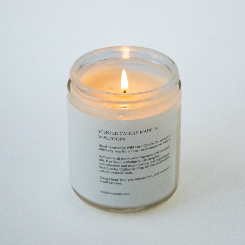 Candle in a glass jar with a label on a white background